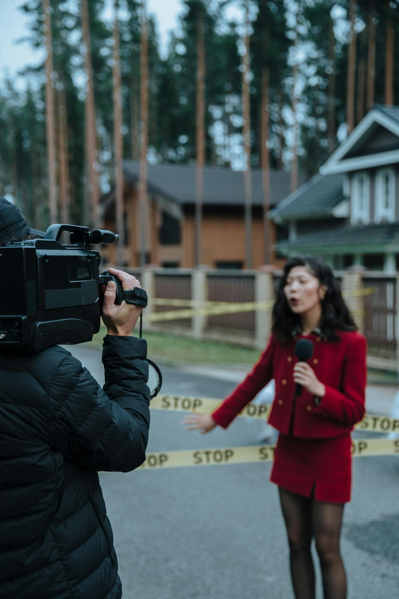 A female reporter conducts a live report at an outdoor crime scene with a cameraman capturing the footage.
